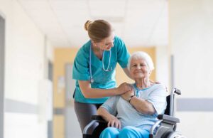 Caregivers assisting older residents in a bright common room during a daily activity.