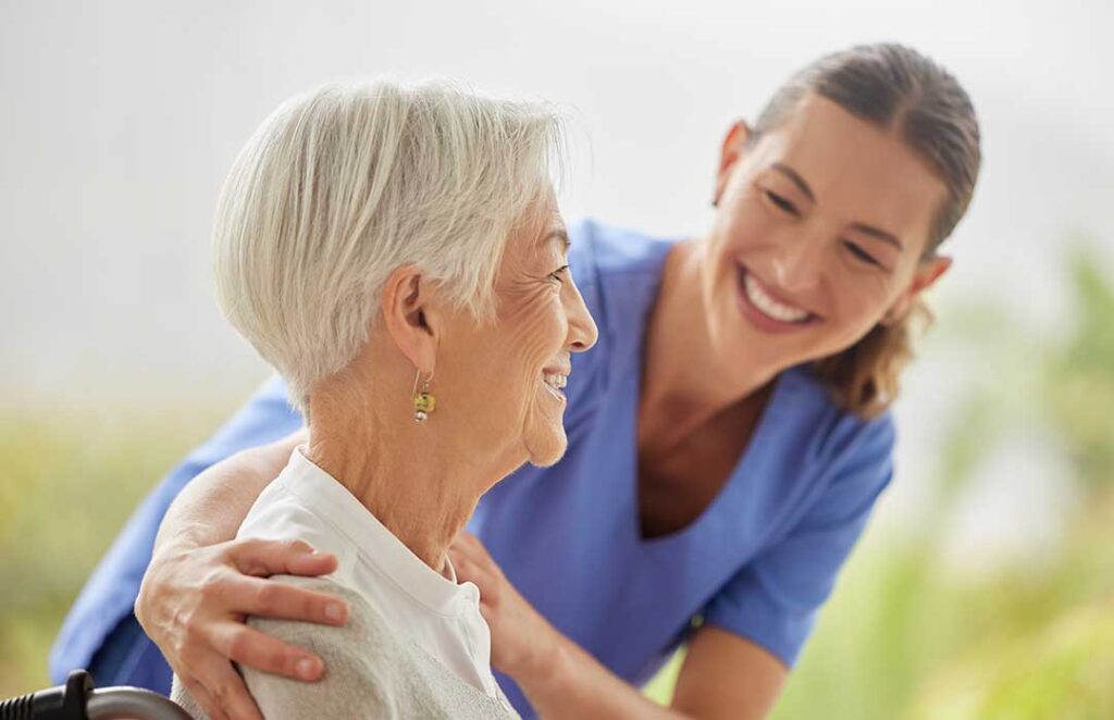 A caregiver offering comfort to an elderly resident in a warmly lit living room with family nearby.